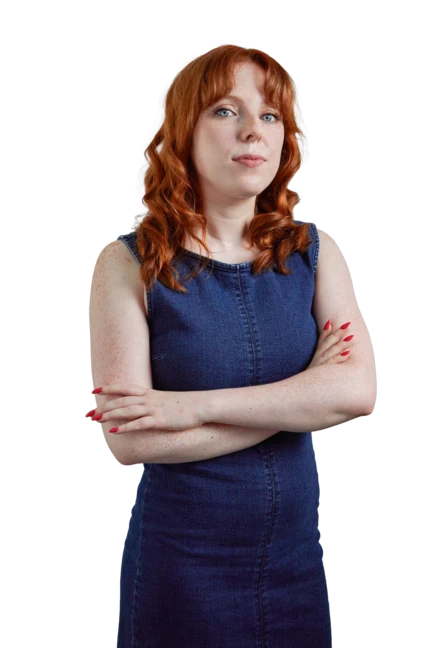 Liv is wearing a black tank top and leaning on a wooden stool with one hand as she looks directly into the camera smiling.